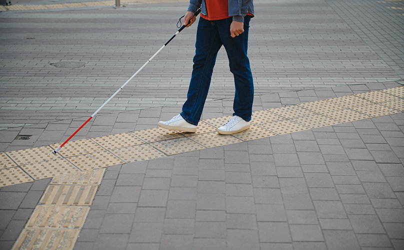 blind man using a white cane to navigate